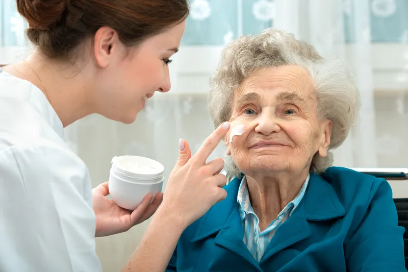 An image of a care worker applying moistener to an elderly persons face